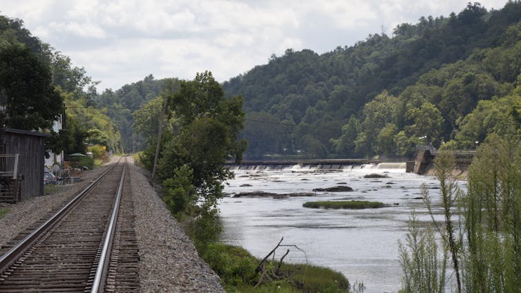 A view of a river and railroad tracks that form a berm protecting buildings.