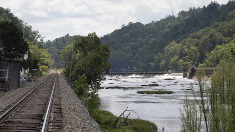 A view of a river and railroad tracks that form a berm protecting buildings.