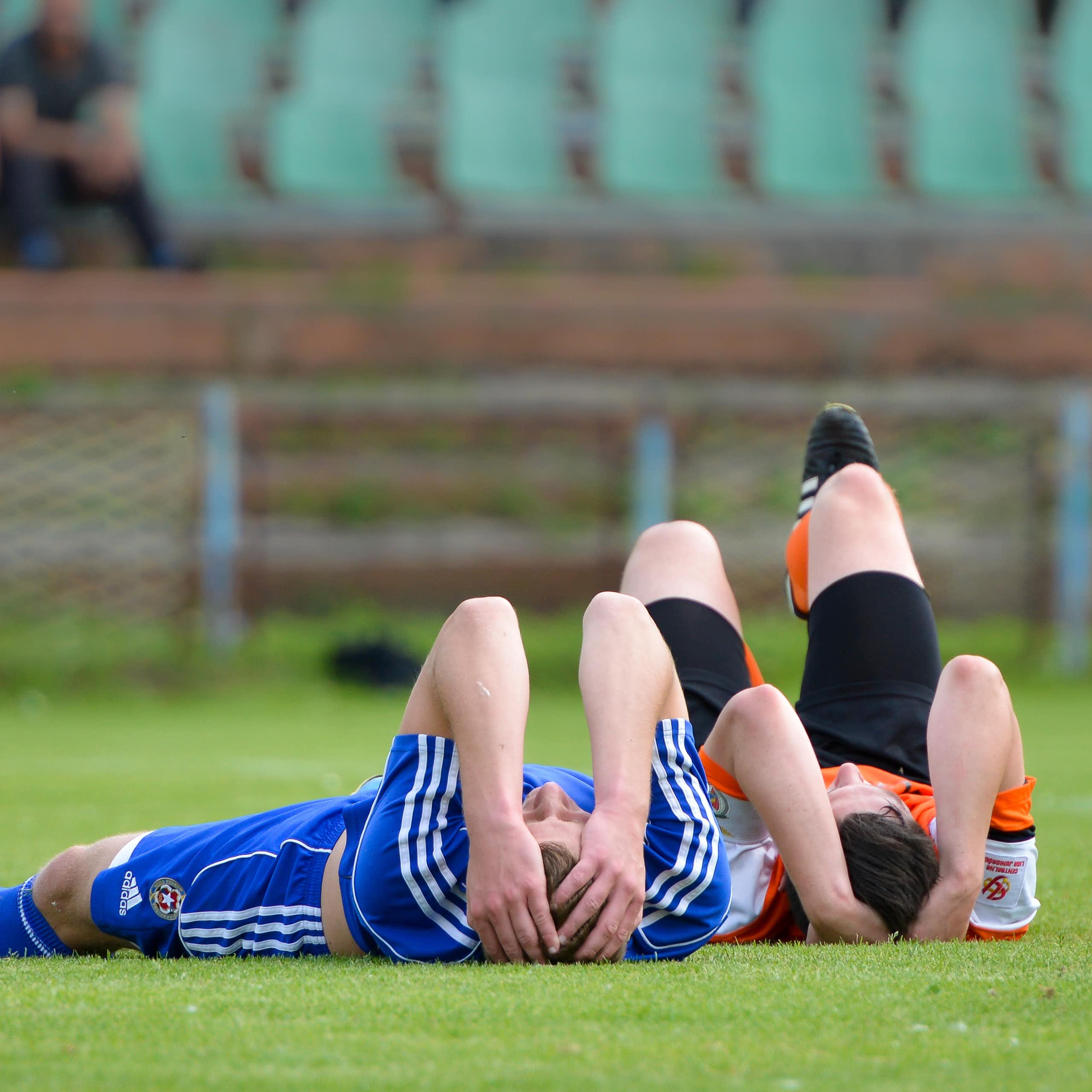 Two junior female soccer players lay injured, holding their heads