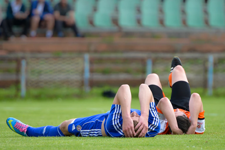 Two junior female soccer players lay injured, holding their heads