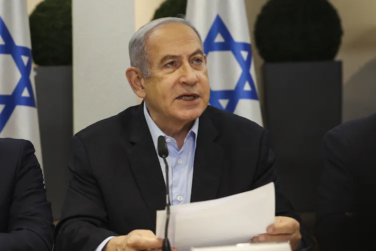 Israeli Prime Minister Benjamin Netanyahu reading in front of Israeli flag