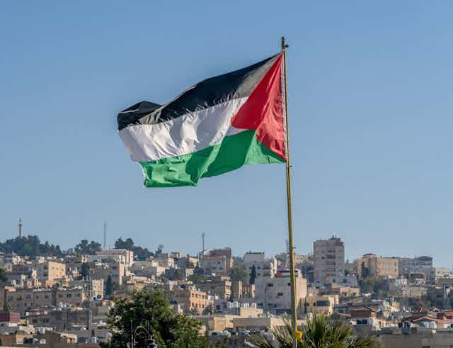 Palestinian flag flying above city horizon