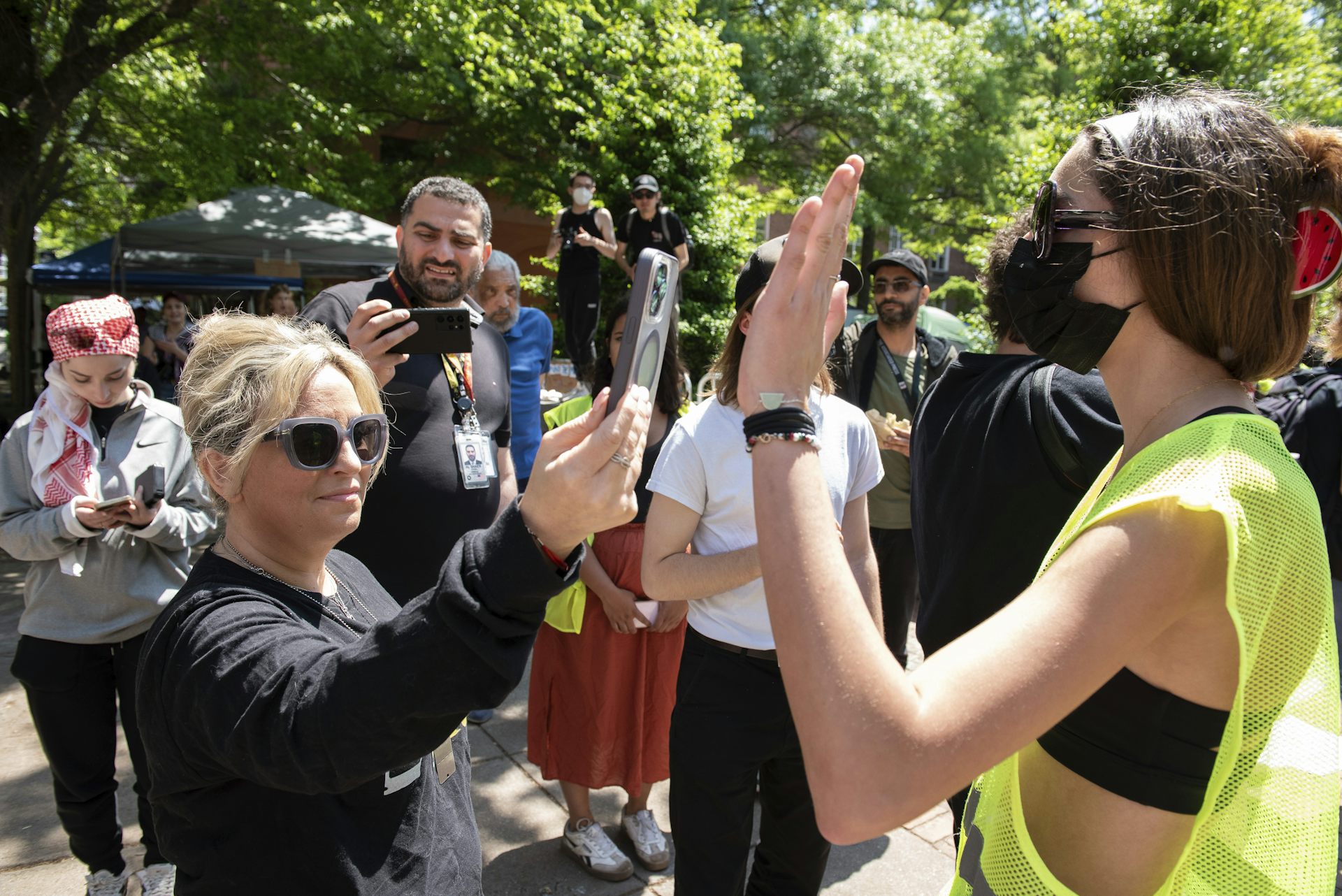 A counterprotester uses a phone to record a pro-Palestinian student.