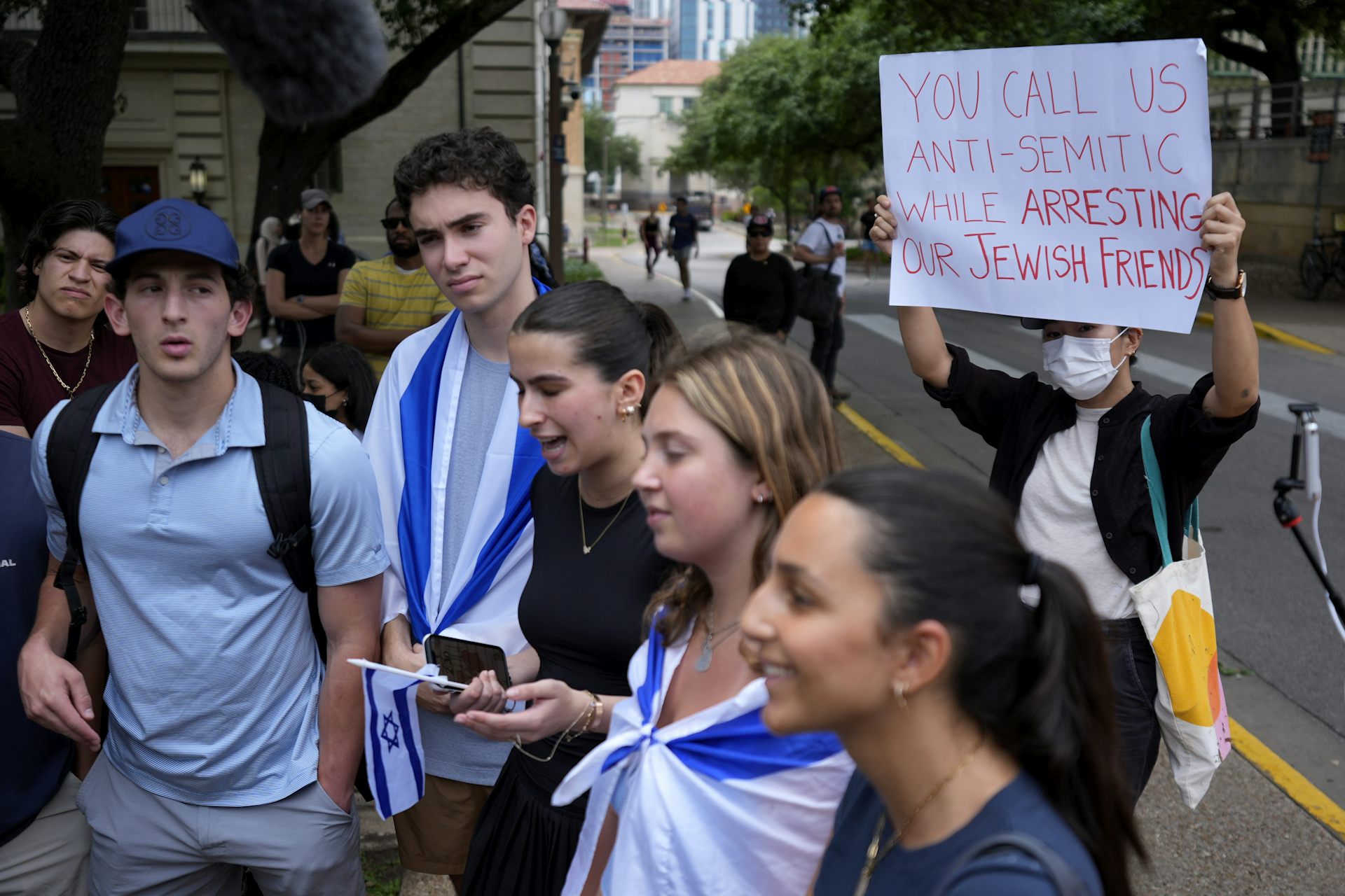 A Pro-Palestinian protester holds up a sign behind Jewish students.