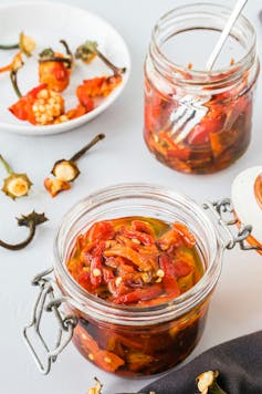 A jar of red peppers in oil.