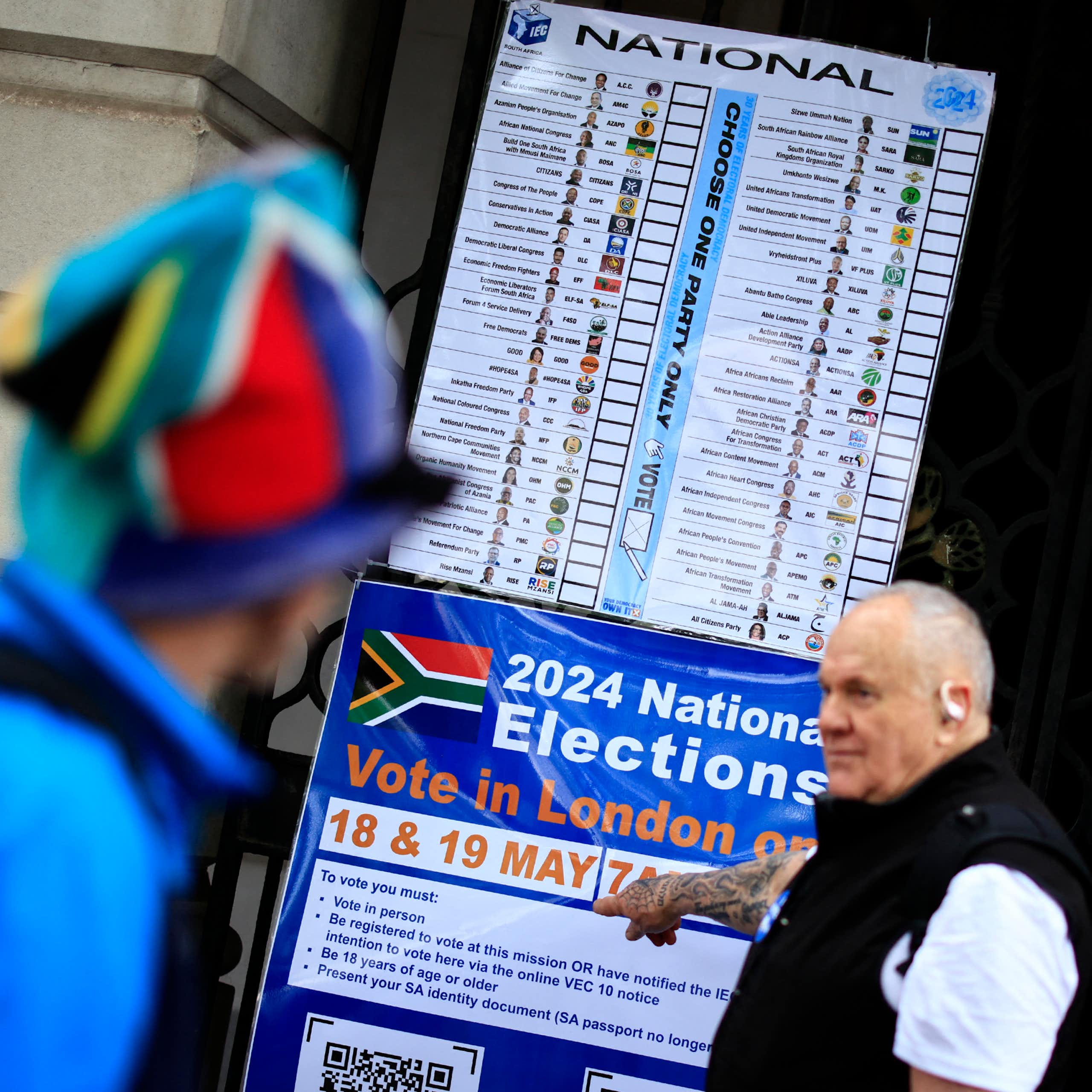 A man points to an information poster outside the South African High Commission in central London about South Africa's 2024 general election.
