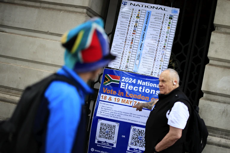 A man points to an information poster outside the South African High Commission in central London about South Africa's 2024 general election.