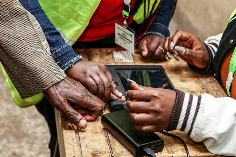 A person's finger is held against a scanner on a rough wooden table