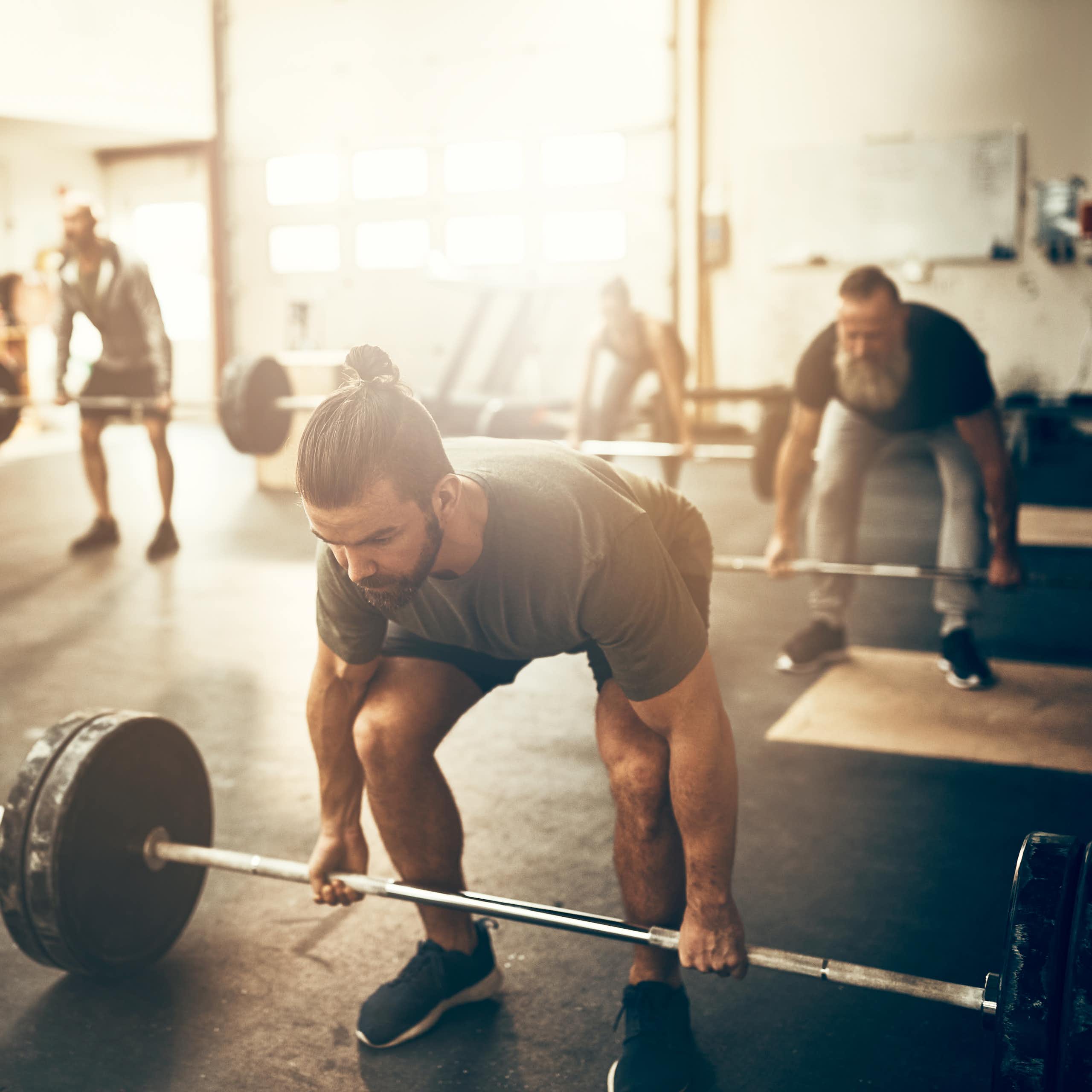 A class of people prepare to do deadlifts in the gym.