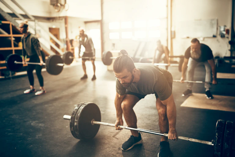 A class of people prepare to do deadlifts in the gym.
