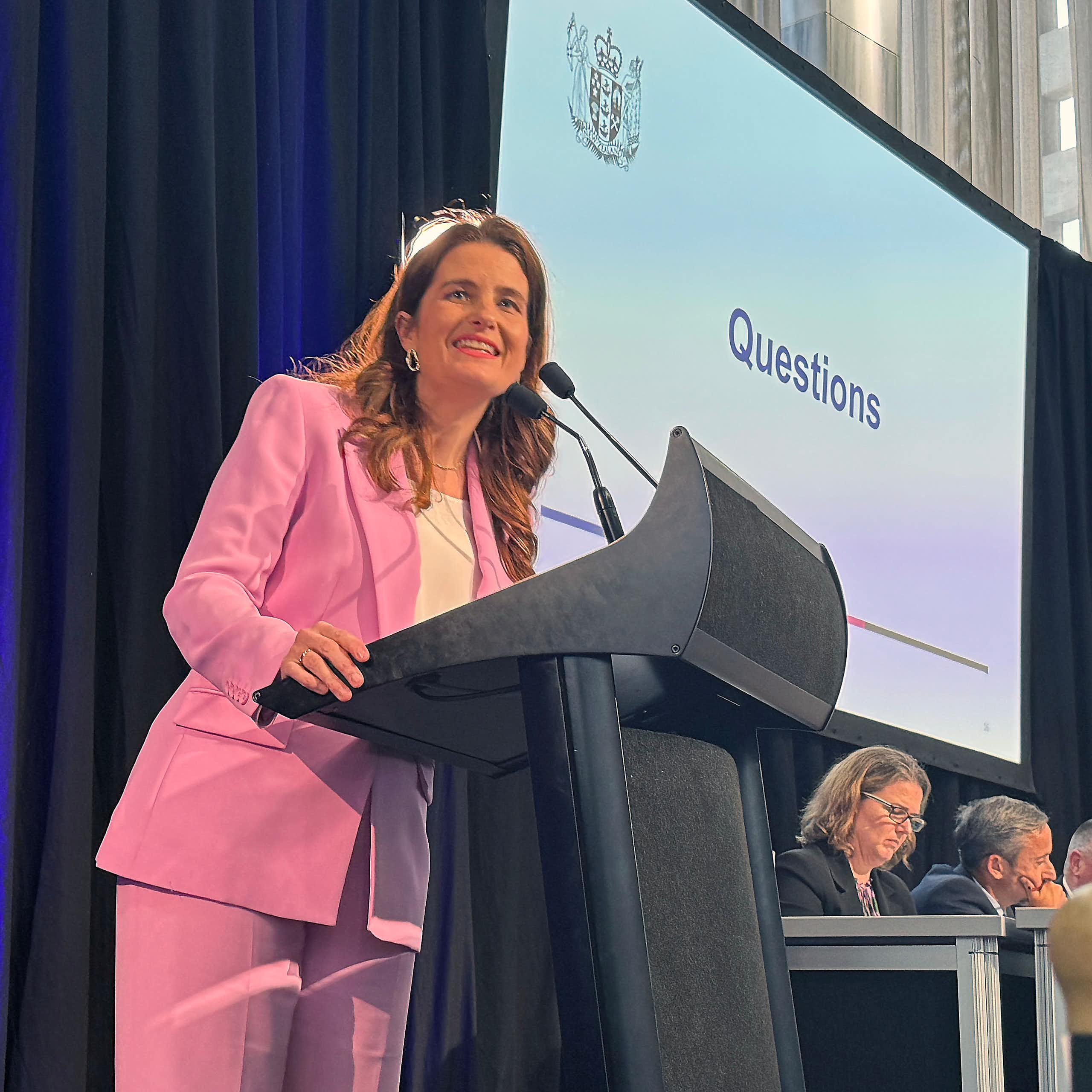 Woman in pink suit stands at lectern