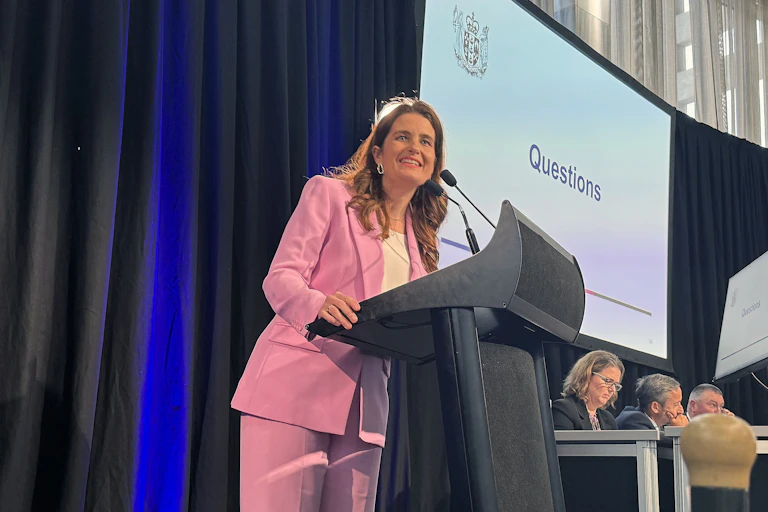 Woman in pink suit stands at lectern