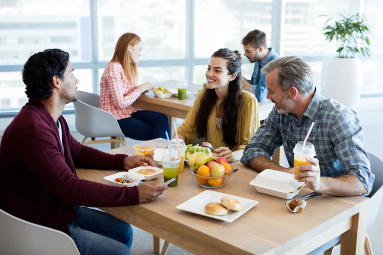 Two men and a woman sitting at a table sharing a meal