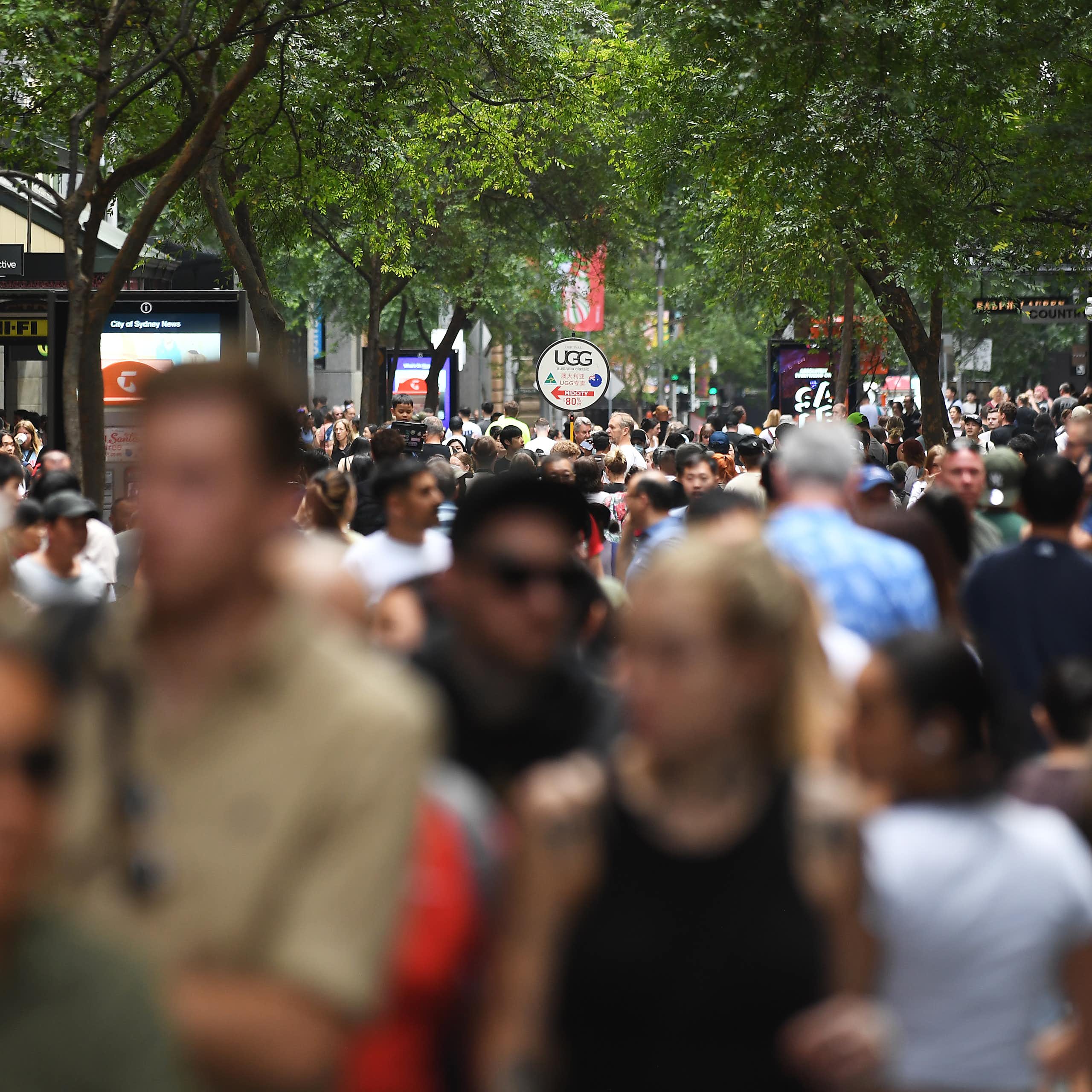 A blurry crowd of diverse people on a busy street
