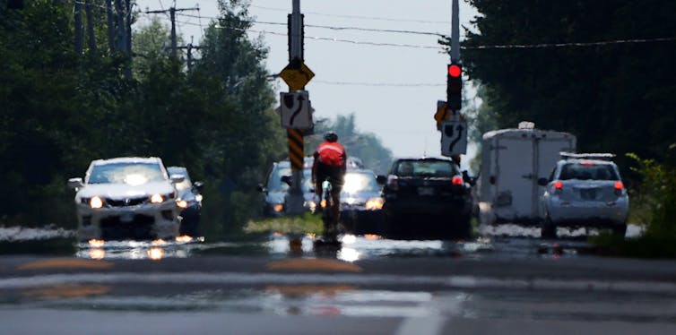Cars and a cyclist at an intersection with summer haze