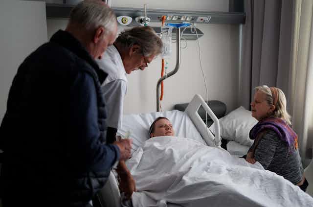  Le docteur Yves de Locht (L) et Wim Distelmans, professeur en soins palliatifs, arrivent dans la chambre d'hôpital pour l'euthanasie de Lydie Imhoff (C) tandis que son accompagnatrice Marie-Josée Rousseaux (D) lui tient la main dans un hôpital en Belgique, le 1er février 2024.