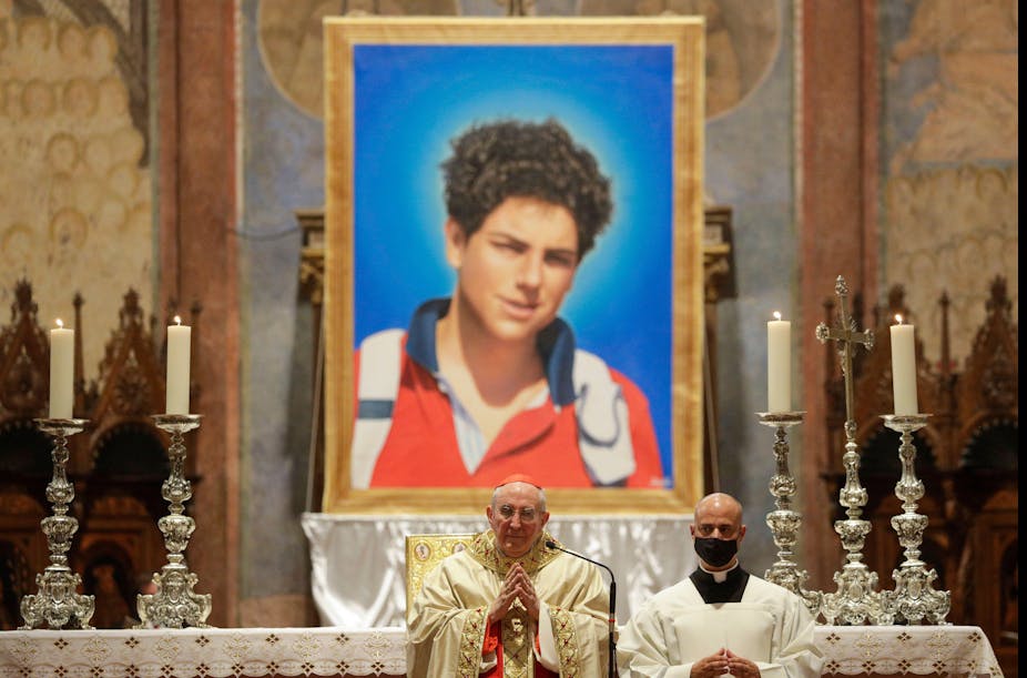 The Pope in front of an altar with a huge picture of Carlo Acutis on it.
