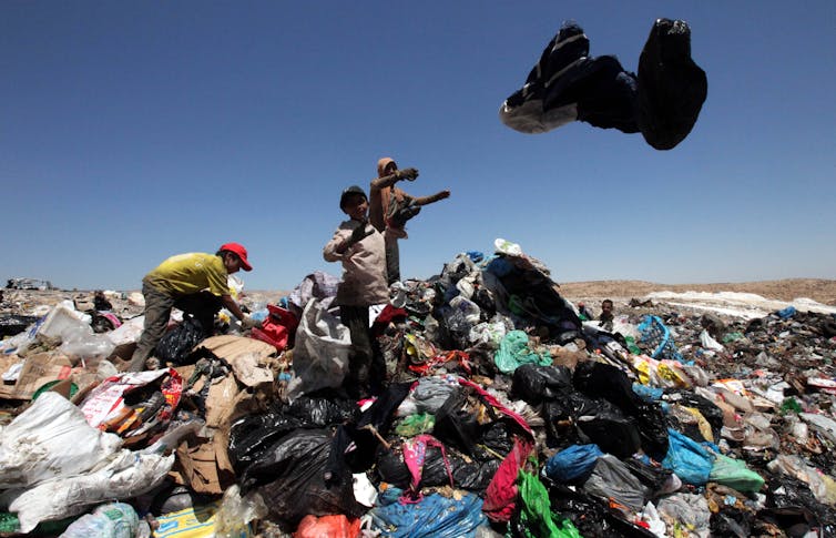 Children picking through garbage on a sunny day.