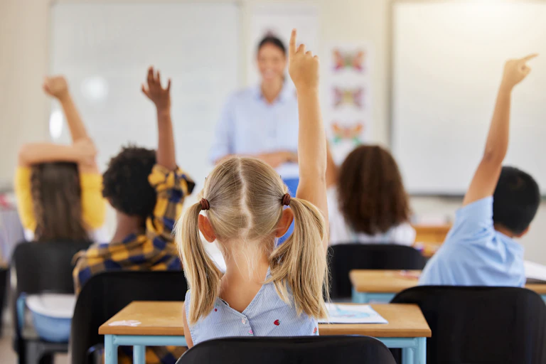 Children raising hands in classroom