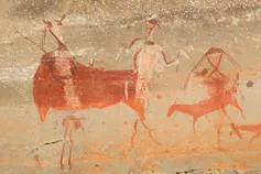 An ancient rock painting of humans hunting animals