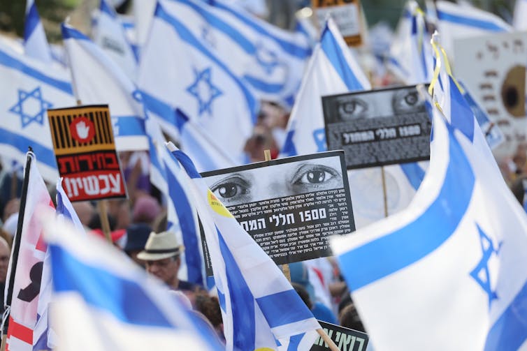 People wave flgas and carry anti-government banners during a protest in Jerusalem, May 2024.