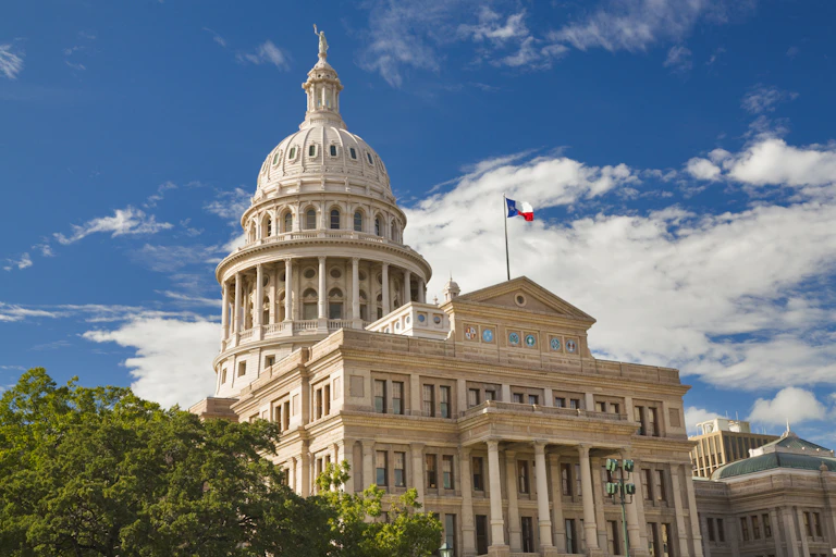 A domed building stands against the blue sky and white clouds.