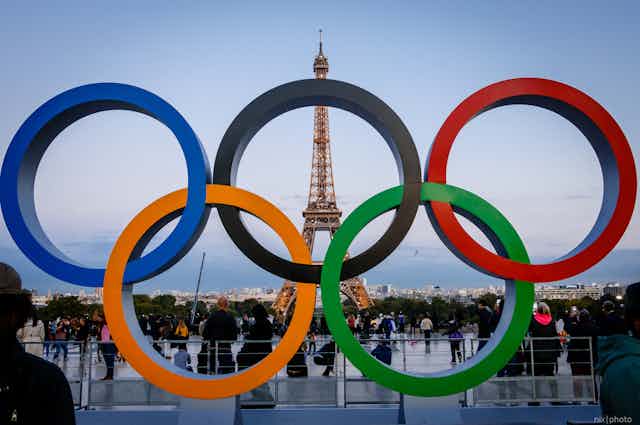 Five Olympic rings with the Eiffel Tower in the background.