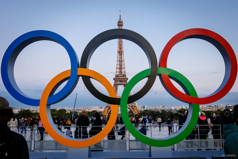 Five Olympic rings with the Eiffel Tower in the background.