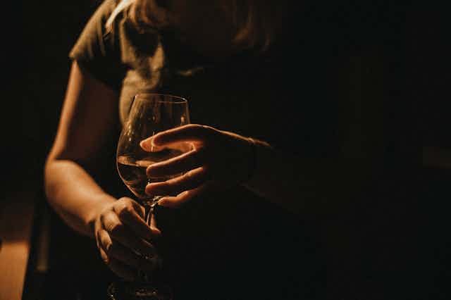 Close-up of person holding glass of wine between two hands