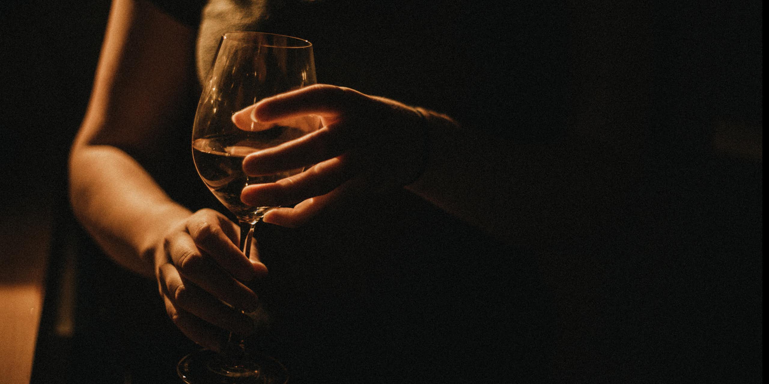 Close-up of person holding glass of wine between two hands