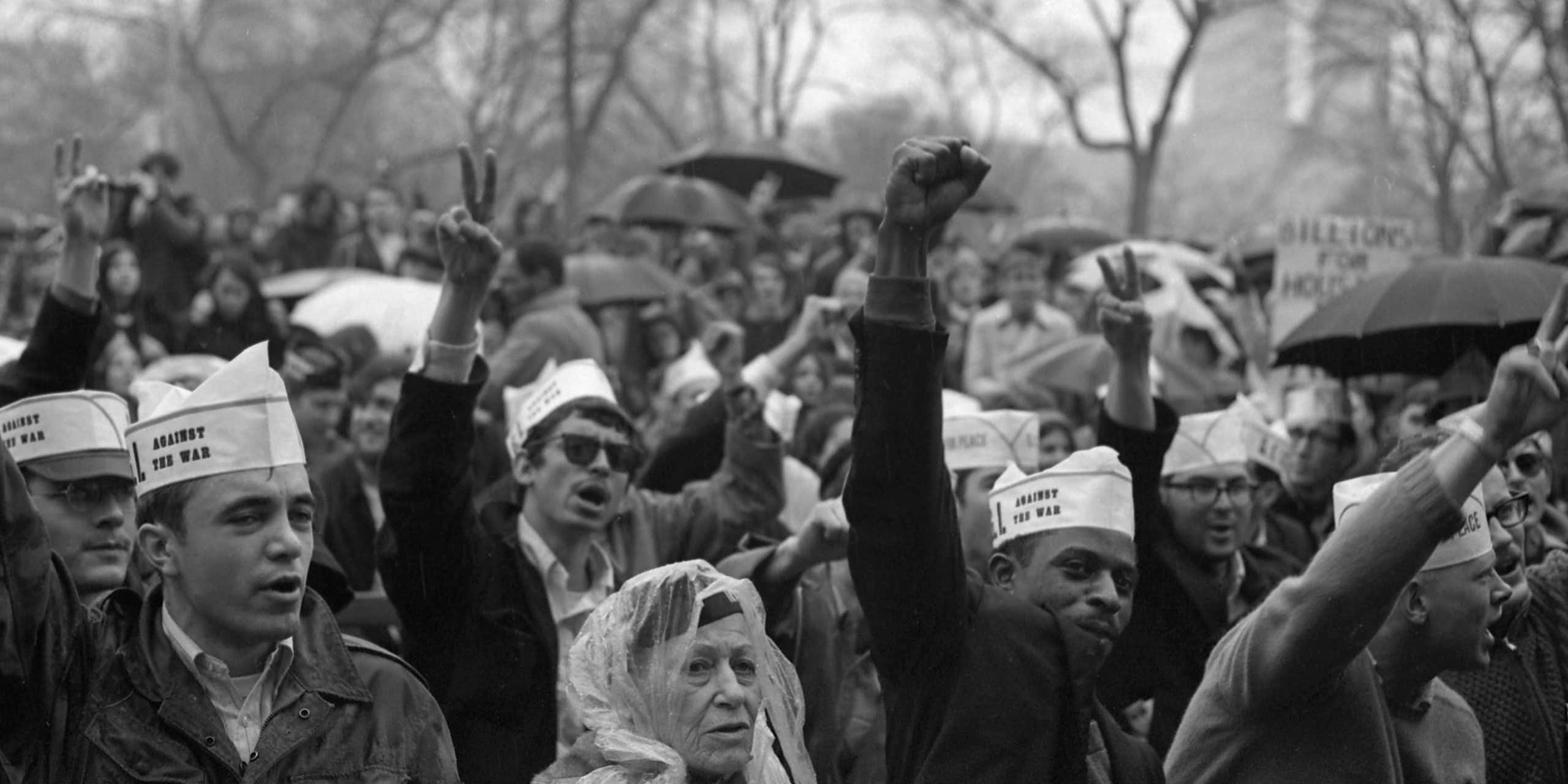 A crowd of demonstrators are raising their fists in protest aganst the Vietnam War. 