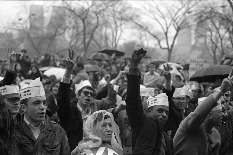 A crowd of demonstrators are raising their fists in protest aganst the Vietnam War.