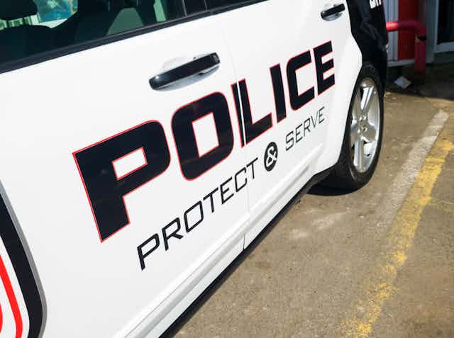 A police car is emblazoned with the words "protect and serve."