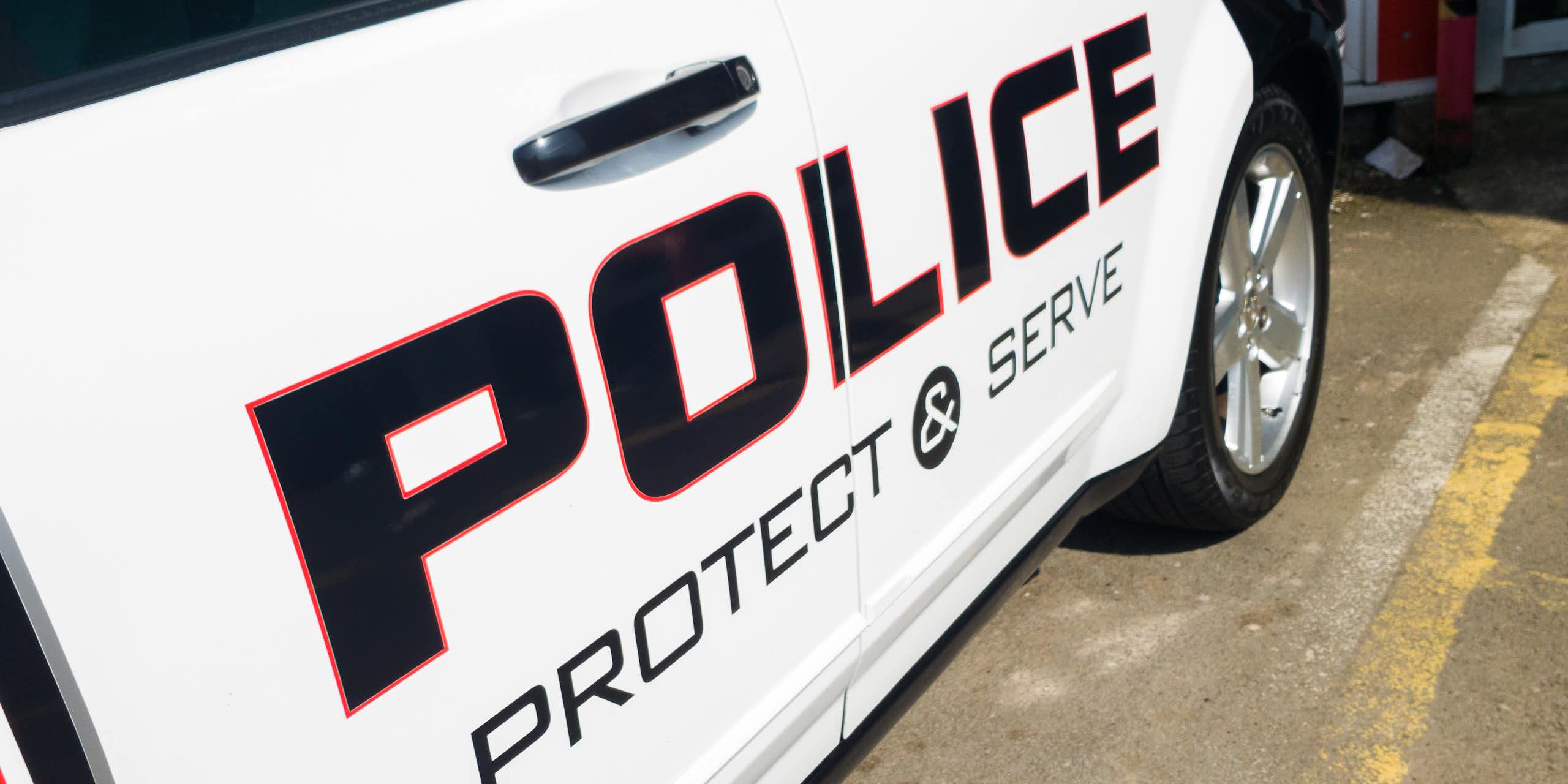 A police car is emblazoned with the words "protect and serve."