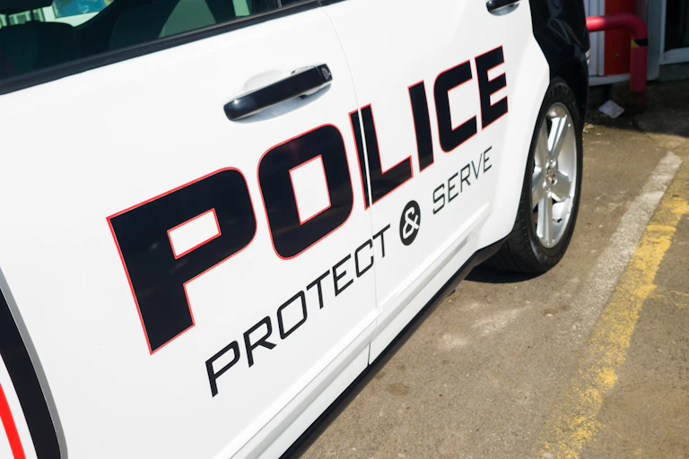 A police car is emblazoned with the words "protect and serve."