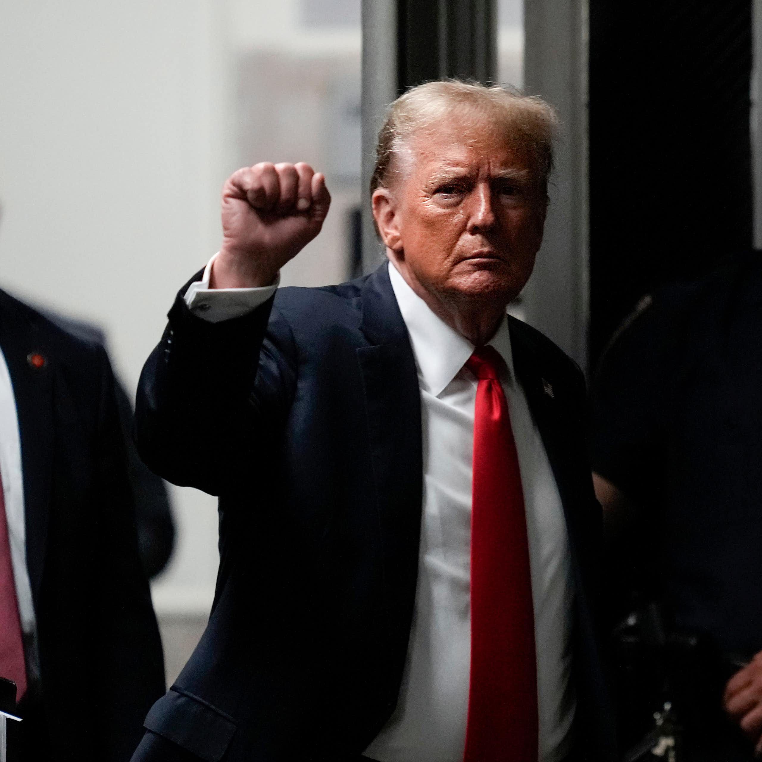 Trump holds up his fist as he walks into a court building