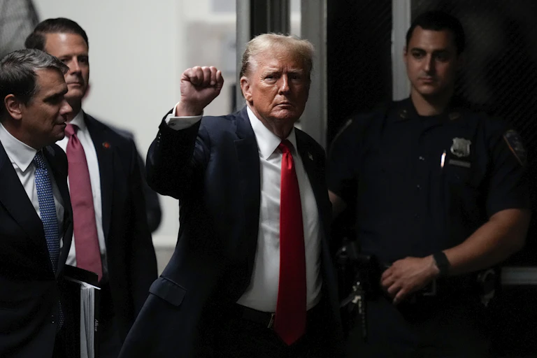 Trump holds up his fist as he walks into a court building
