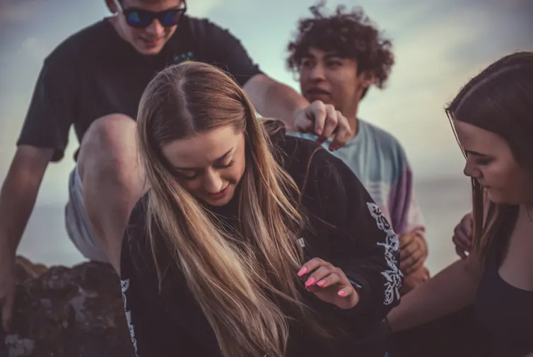 Teens sit on a rock by the ocean