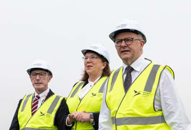 Minister Catherine King (centre) and Prime Minister Anthony Albanese (right) wear hardhats and hi-viz vests at an infrastructure announcement