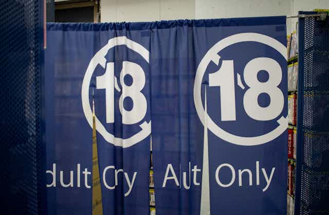 A flimsy blue curtain saying no 18 and adult only hung in a store.