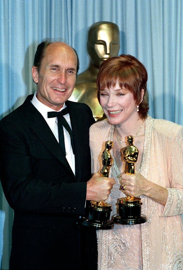 The two actors hold their statuettes.