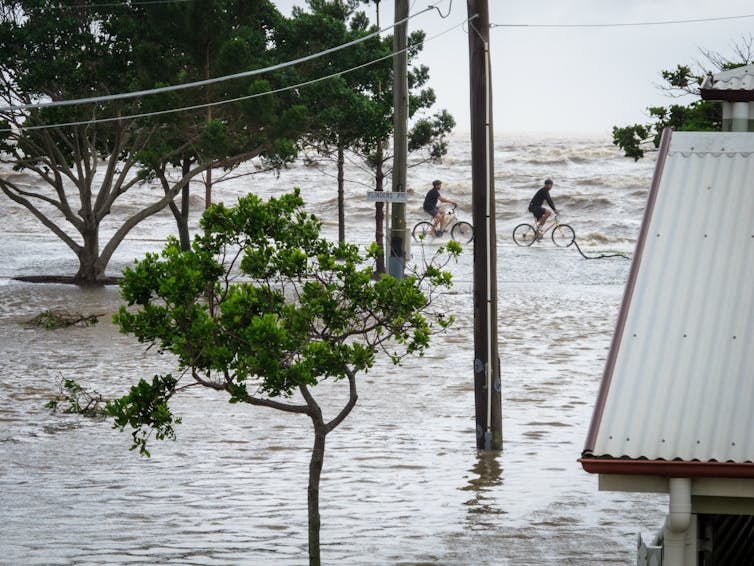 cyclists on top of flooded seawall