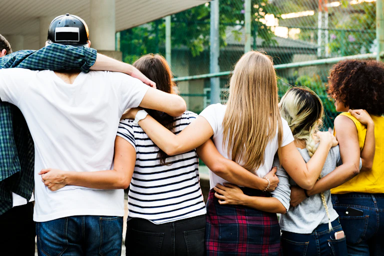 Young people with arms around each other facing away from camera