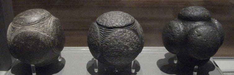 Three carved stone balls on display.