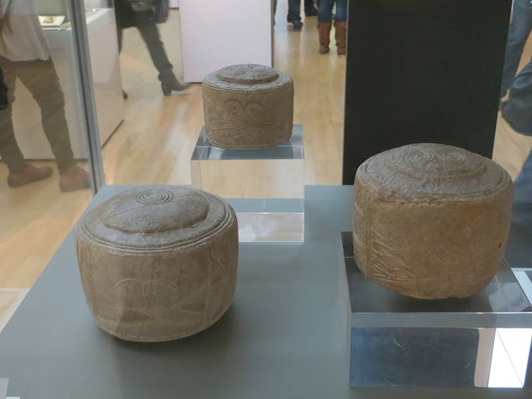 Three white carved drums on display.