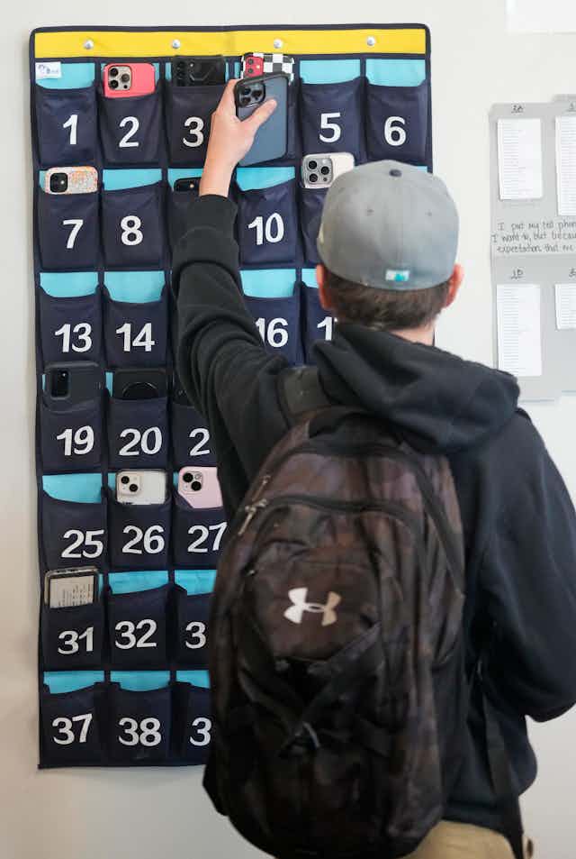 Un élève du primaire place son téléphone intelligent dans un étui avant d'entrer dans sa classe.