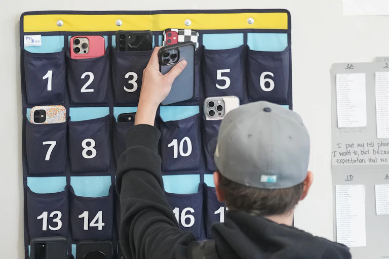Un élève du primaire place son téléphone intelligent dans un étui avant d'entrer dans sa classe.