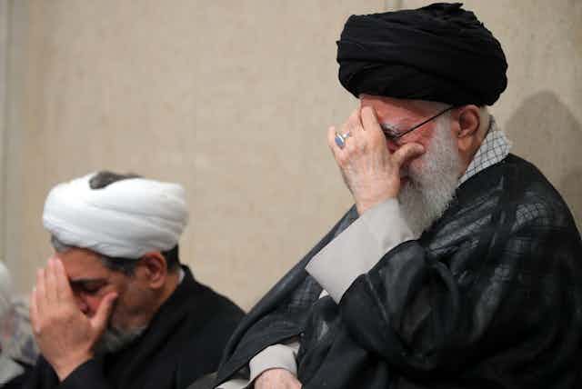 Iran's supreme leader Ali Khamenei holds his head in his hand.