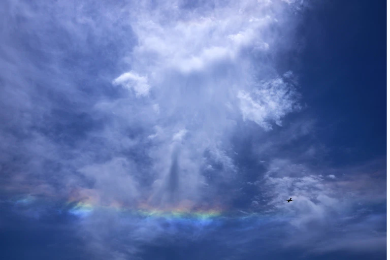 A plane flies amongst coulds.