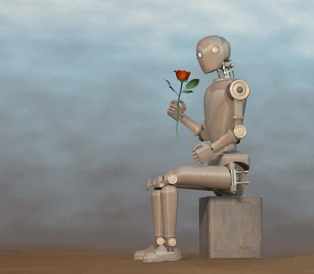 a humanoid robot sitting on a block holding a rosee too its face